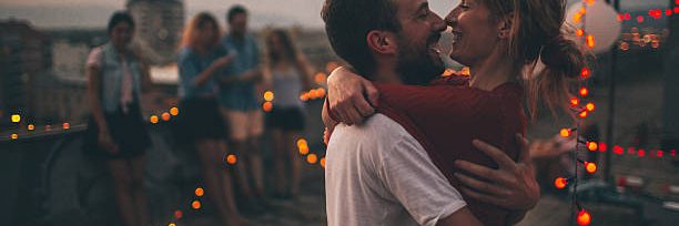 Couple of friends having a party on the rooftop of the building at sunset;